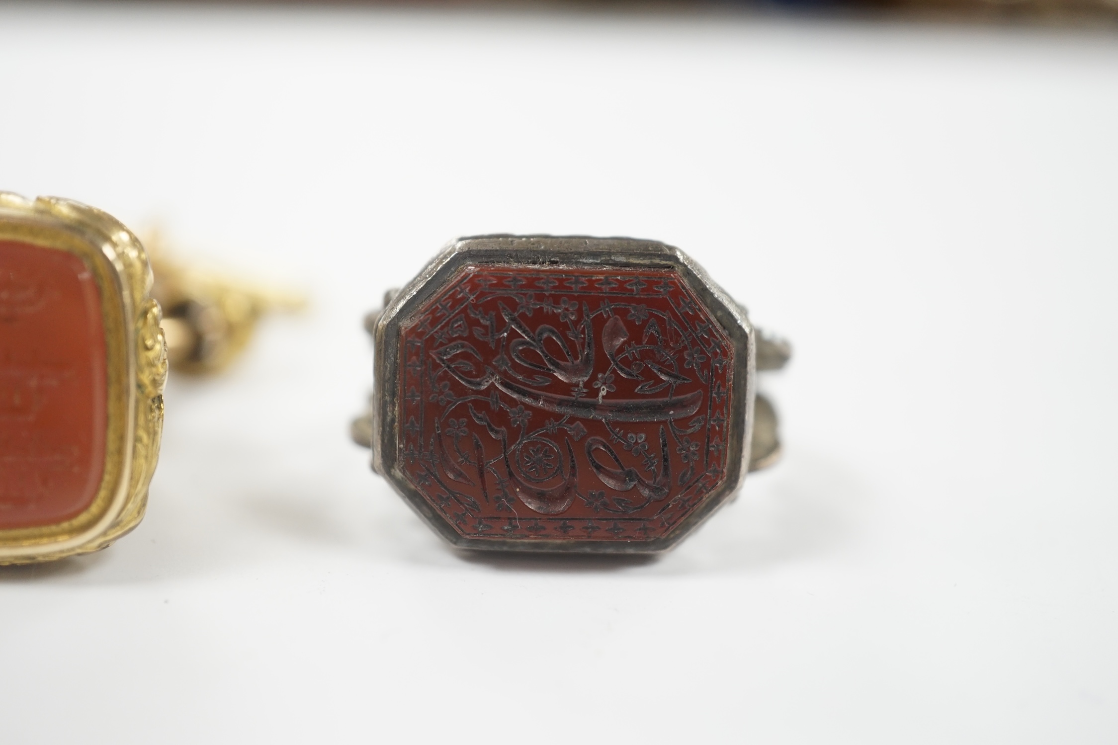 A 19th century gilt metal overlaid and carnelian set fob seal, 36mm, together with a white metal and chalcedony set fob seal, the matrix carved with Persian script.